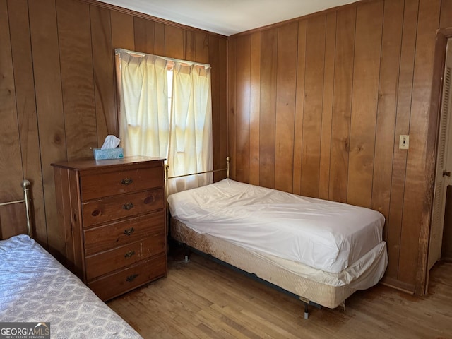 bedroom with wooden walls and light wood-type flooring