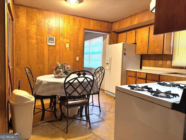 kitchen with white appliances, wood walls, and sink