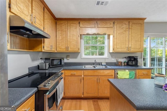 kitchen with stainless steel appliances, dark countertops, visible vents, and under cabinet range hood