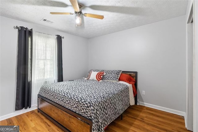 bedroom with a textured ceiling, visible vents, and wood finished floors