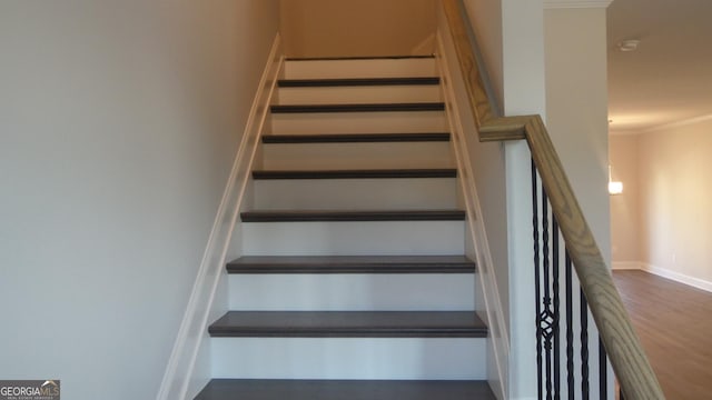 stairs featuring wood-type flooring and ornamental molding