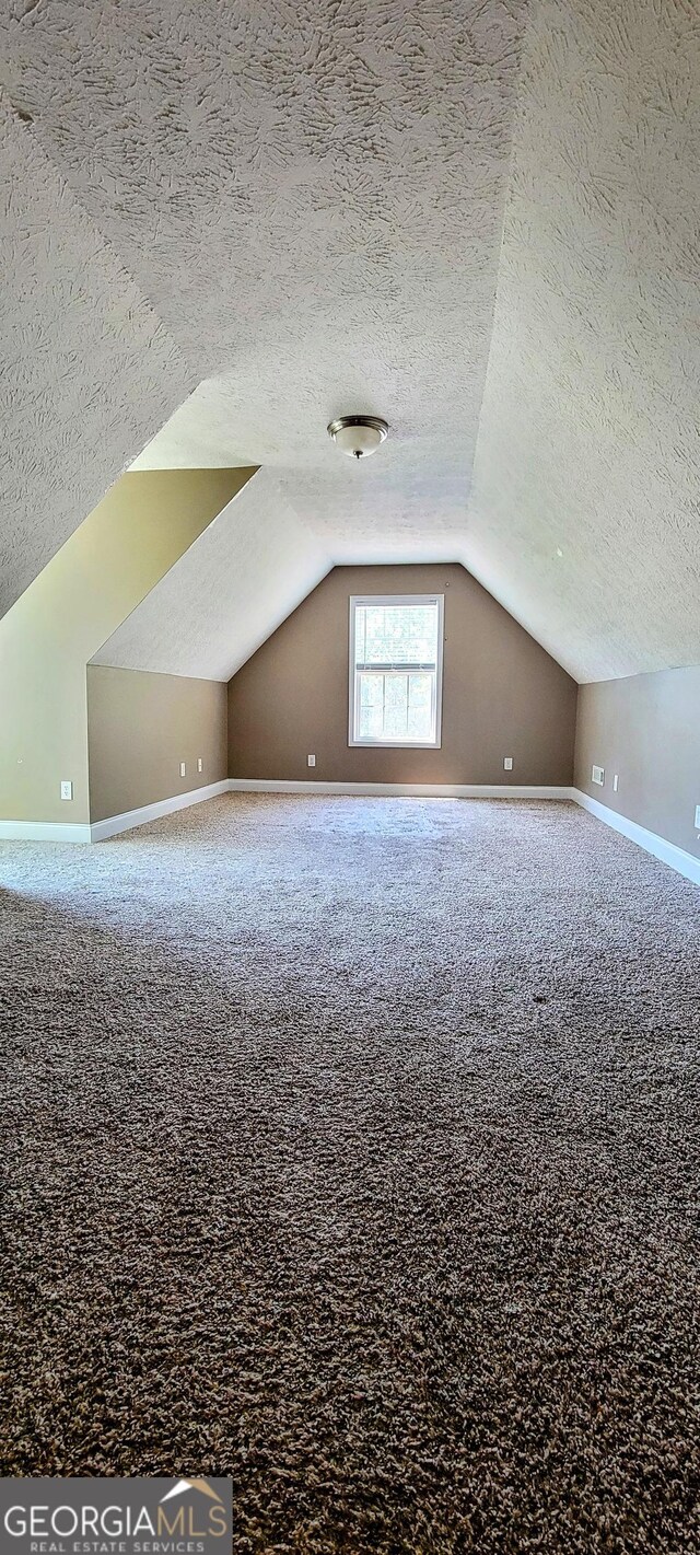 bonus room with carpet floors, a textured ceiling, and vaulted ceiling