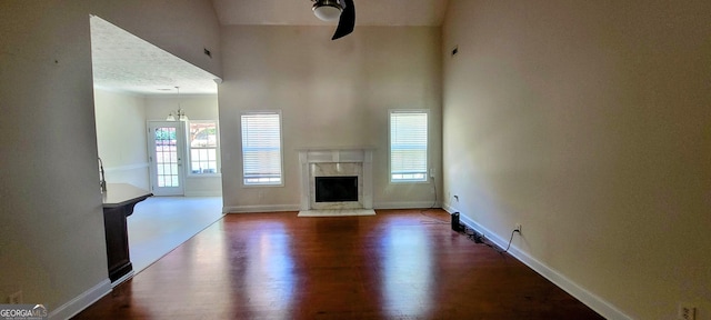 unfurnished living room featuring a textured ceiling, a premium fireplace, hardwood / wood-style floors, and ceiling fan with notable chandelier