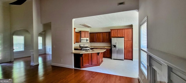 kitchen with stainless steel appliances, a kitchen island with sink, and dark wood-type flooring