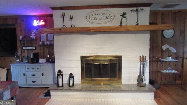 2296 Athens Rd, Royston, GA 30662 - living room featuring visible vents, a brick fireplace, wood finished floors, and wooden walls