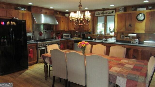 2296 Athens Rd, Royston, GA 30662 - kitchen featuring brown cabinets, stainless steel appliances, light wood-style floors, wall chimney exhaust hood, and a chandelier