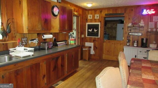 kitchen with light wood-type flooring and wood walls