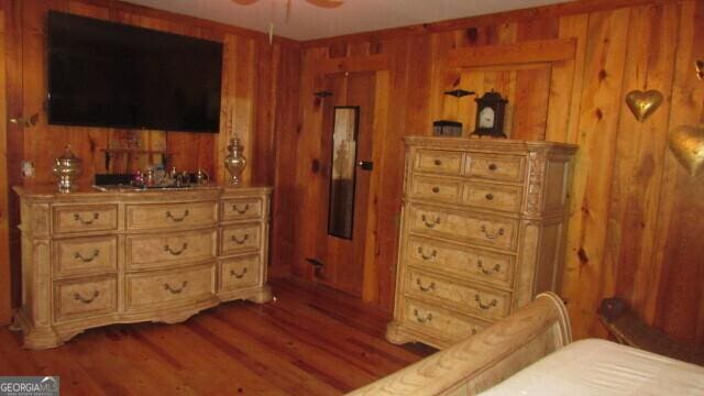 bedroom with hardwood / wood-style flooring, bar, and wood walls