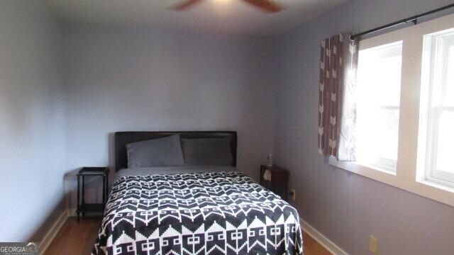 bedroom featuring multiple windows, hardwood / wood-style floors, and ceiling fan