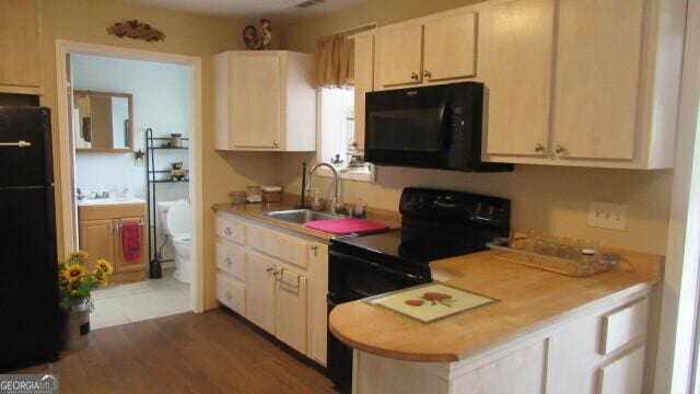 kitchen with light brown cabinetry, sink, black appliances, and dark hardwood / wood-style floors