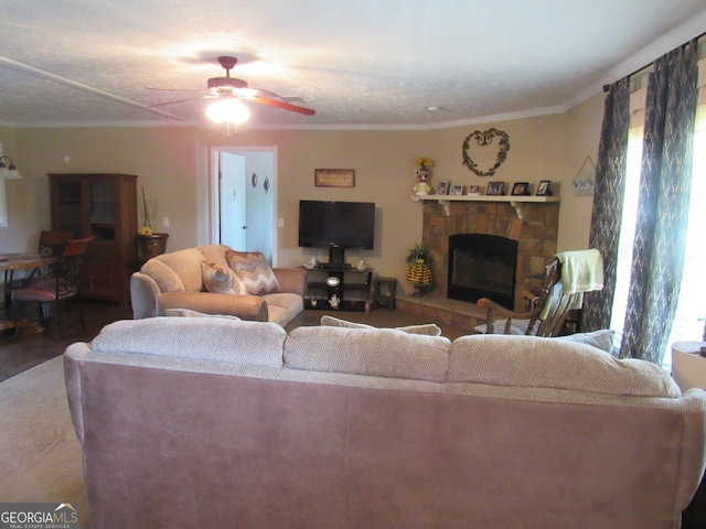 living room with hardwood / wood-style flooring, ceiling fan, ornamental molding, and a stone fireplace