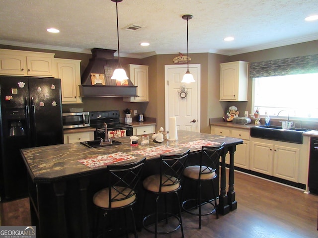 kitchen featuring black appliances, sink, custom exhaust hood, and a center island with sink