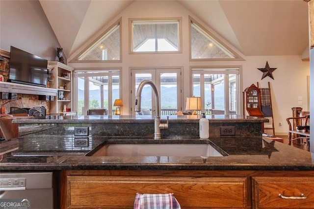 kitchen with dark stone countertops, high vaulted ceiling, sink, and dishwasher