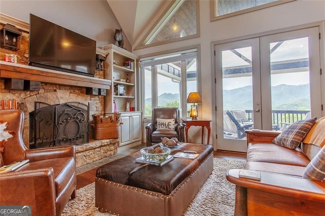 living room featuring a stone fireplace, light hardwood / wood-style floors, a mountain view, and plenty of natural light