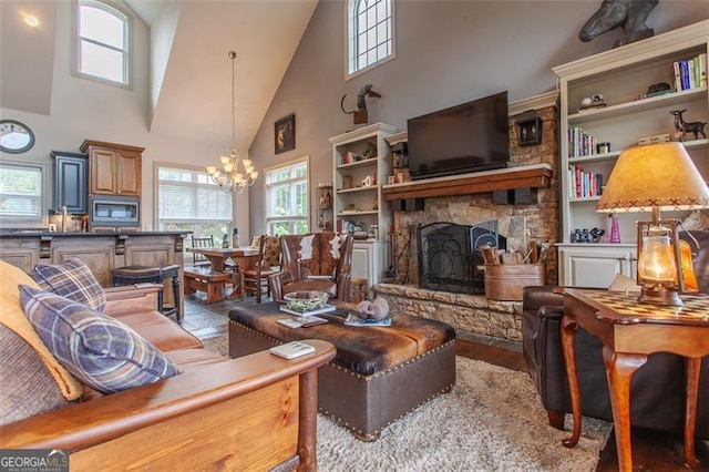 living room with a high ceiling, a fireplace, a chandelier, and hardwood / wood-style flooring