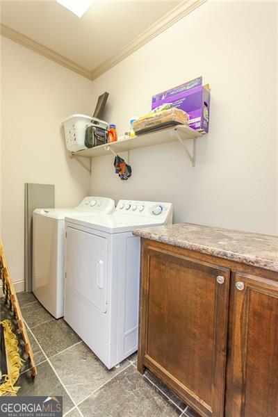 laundry room with ornamental molding, washer and dryer, and tile patterned flooring