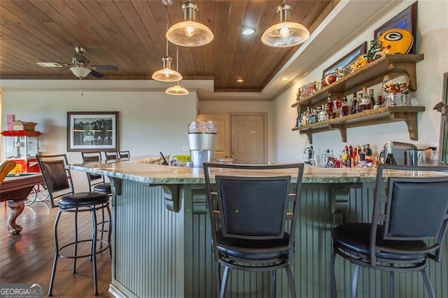 kitchen featuring ceiling fan, hardwood / wood-style flooring, ornamental molding, a kitchen bar, and wood ceiling