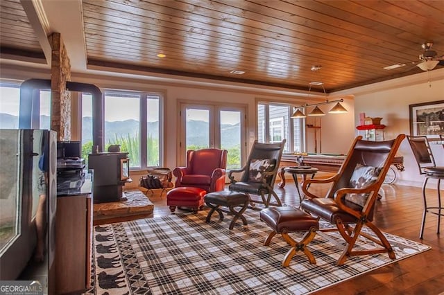 living room with hardwood / wood-style flooring, wood ceiling, a mountain view, and ceiling fan