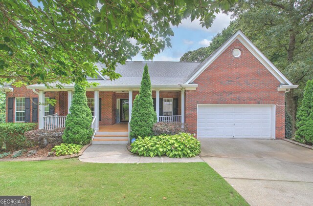 view of front of property featuring covered porch, a garage, and a front lawn