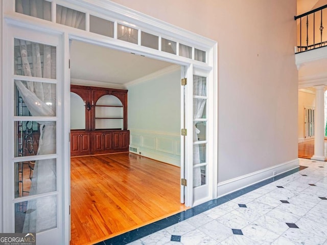 entrance foyer with decorative columns, light hardwood / wood-style flooring, and ornamental molding