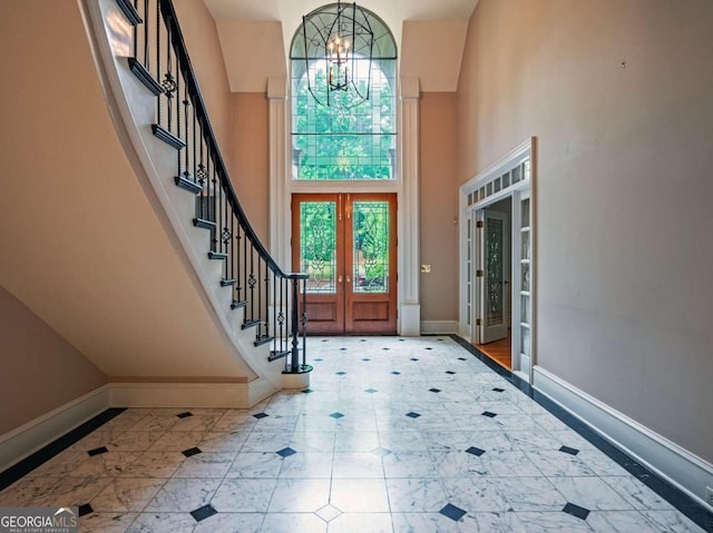 foyer featuring a notable chandelier, french doors, a towering ceiling, and tile patterned flooring