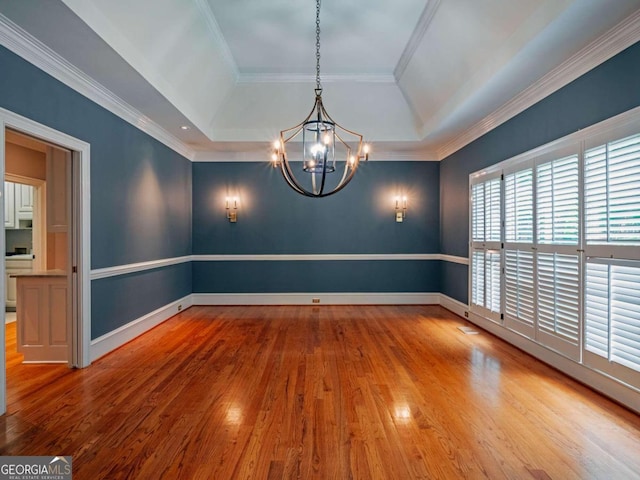 unfurnished room featuring an inviting chandelier, crown molding, hardwood / wood-style floors, and a tray ceiling