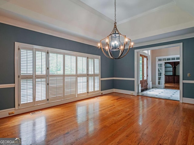 spare room featuring a chandelier, crown molding, and wood-type flooring