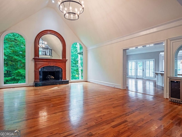 unfurnished living room featuring a fireplace, beverage cooler, wood-type flooring, and vaulted ceiling