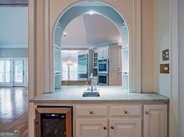 kitchen with stainless steel appliances, sink, wine cooler, white cabinetry, and wood-type flooring