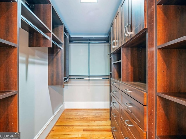 walk in closet with light hardwood / wood-style floors