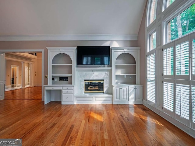 unfurnished living room featuring built in shelves, a premium fireplace, and wood-type flooring