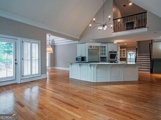 kitchen with appliances with stainless steel finishes, pendant lighting, white cabinets, and high vaulted ceiling