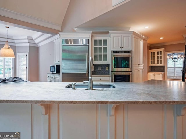 kitchen with decorative backsplash, stainless steel appliances, decorative light fixtures, and ornamental molding