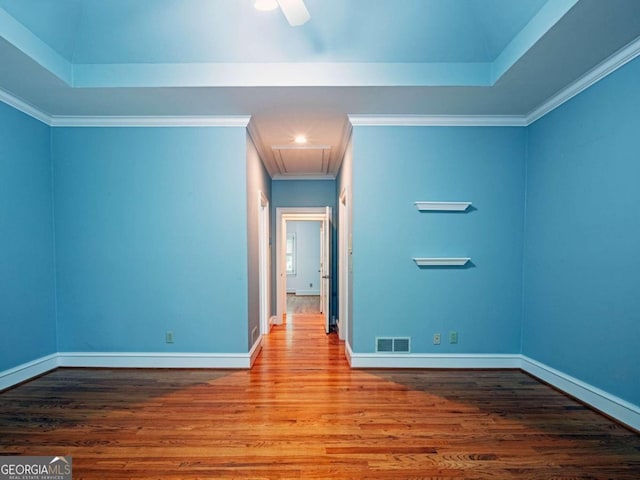 interior space featuring a raised ceiling, ornamental molding, hardwood / wood-style floors, and ceiling fan