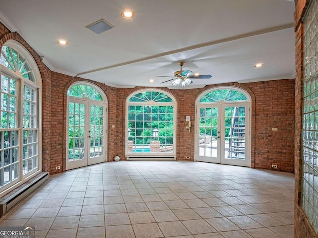 interior space featuring brick wall, ceiling fan, a wealth of natural light, and baseboard heating