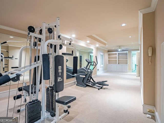 gym with a tray ceiling, crown molding, carpet, and ceiling fan