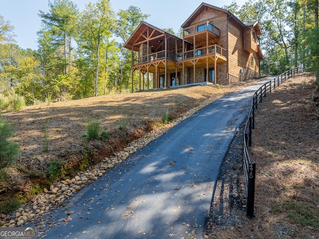 rear view of house with stone siding and driveway