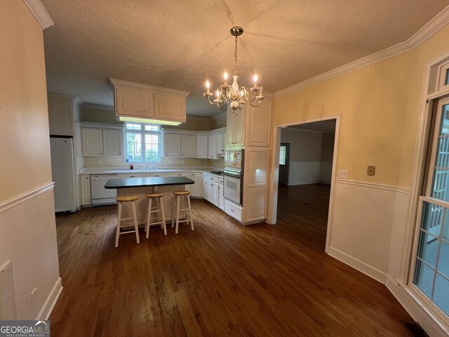 kitchen featuring a notable chandelier, white cabinets, white appliances, a center island, and dark wood-type flooring