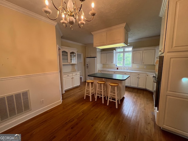 kitchen featuring white cabinets, a kitchen island, dark hardwood / wood-style floors, a notable chandelier, and white fridge with ice dispenser