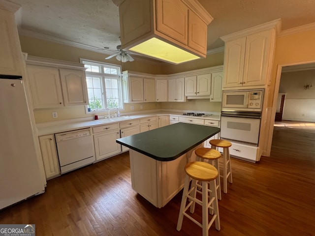 kitchen featuring white appliances, a center island, ceiling fan, dark hardwood / wood-style floors, and sink