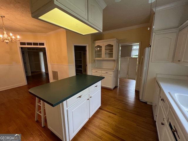 kitchen featuring white cabinets, hardwood / wood-style floors, hanging light fixtures, a kitchen island, and a notable chandelier