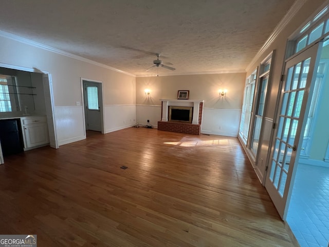 unfurnished living room featuring ornamental molding, a brick fireplace, hardwood / wood-style flooring, and ceiling fan