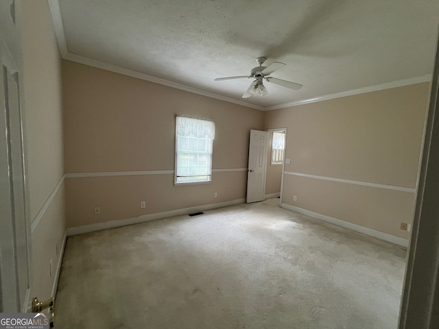 carpeted spare room featuring a textured ceiling, ceiling fan, and crown molding