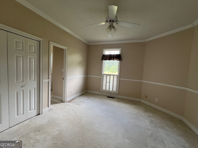 unfurnished bedroom featuring ceiling fan, a closet, light colored carpet, and crown molding