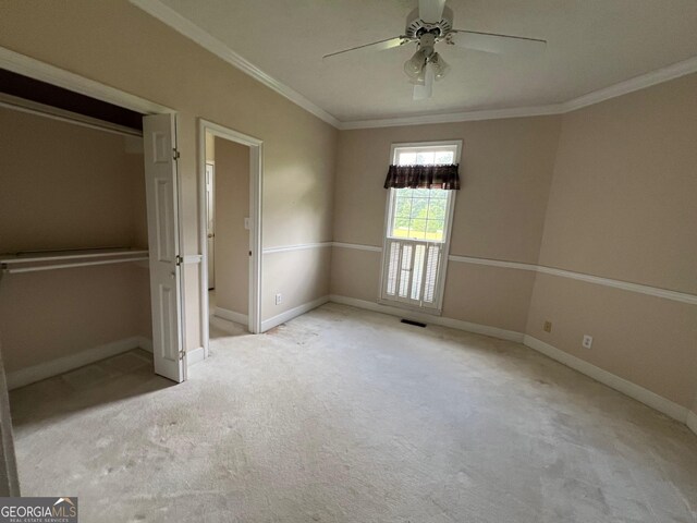 unfurnished bedroom featuring ornamental molding, light colored carpet, and ceiling fan