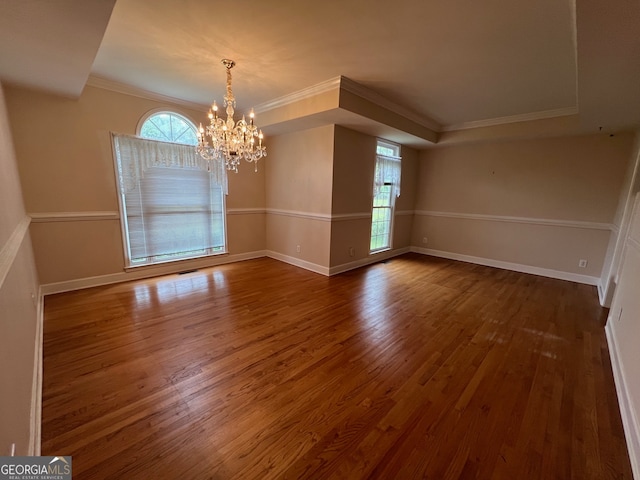 empty room with a wealth of natural light, crown molding, hardwood / wood-style floors, and a chandelier