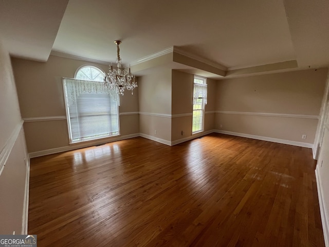 unfurnished room with crown molding, hardwood / wood-style flooring, a raised ceiling, and a notable chandelier