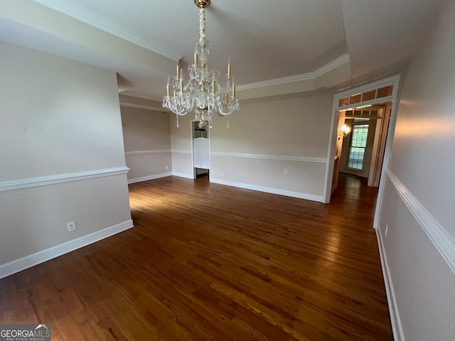 empty room with a notable chandelier, dark hardwood / wood-style flooring, and ornamental molding