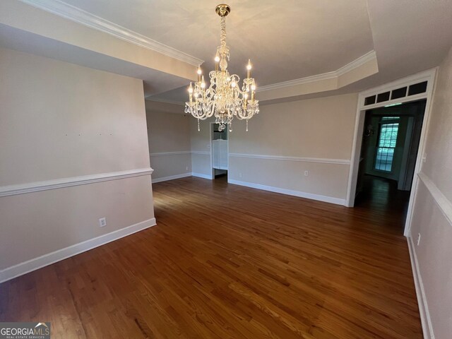 unfurnished room with a tray ceiling, dark wood-type flooring, and a chandelier