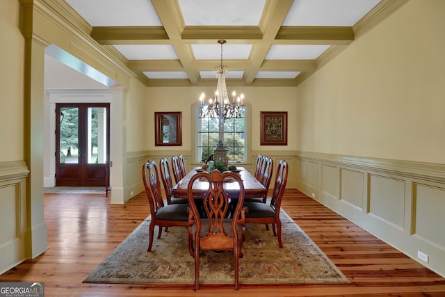 dining space featuring beam ceiling, a notable chandelier, crown molding, light wood-type flooring, and coffered ceiling